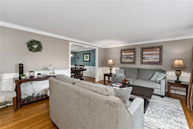 living area with crown molding, wood finished floors, and a wainscoted wall