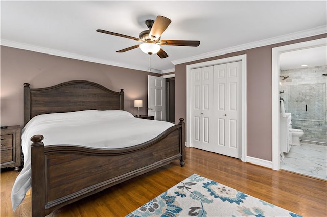 bedroom featuring a closet, baseboards, ceiling fan, ensuite bathroom, and crown molding