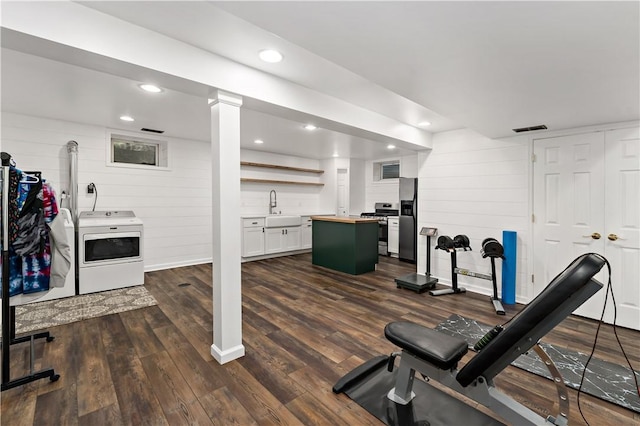exercise room with washer / dryer, a sink, dark wood-style flooring, recessed lighting, and wooden walls