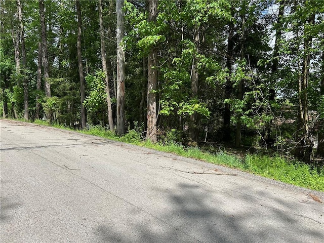view of asphalt road with a view of trees