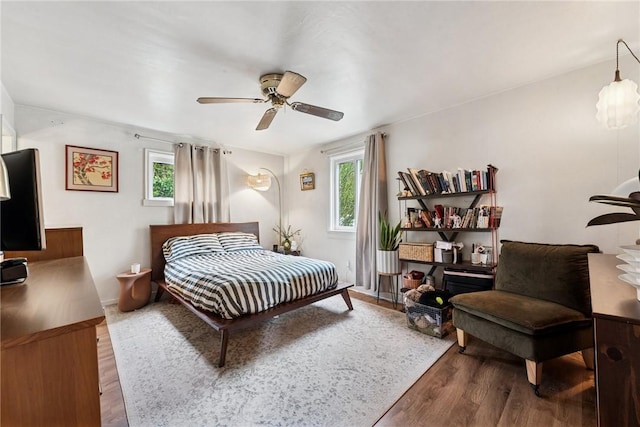 bedroom featuring multiple windows, wood finished floors, and a ceiling fan
