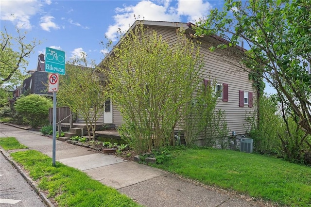view of property exterior with a yard and central AC