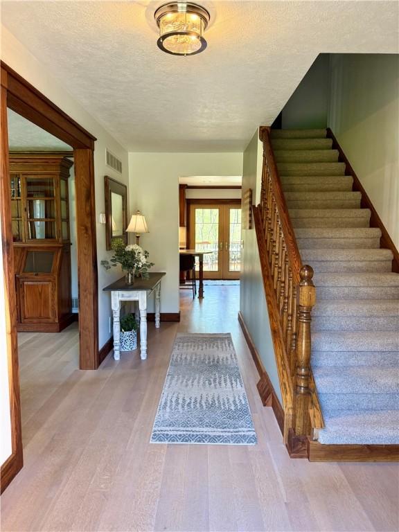 111 Mccall Rd, Franklin Twp But, PA 16001 - foyer entrance with stairway, a textured ceiling, baseboards, wood finished floors, and french doors