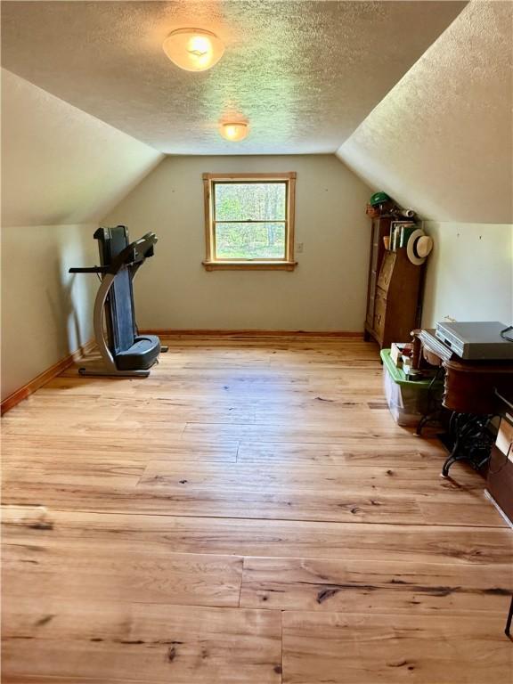 111 Mccall Rd, Franklin Twp But, PA 16001 - additional living space featuring light wood-type flooring, a textured ceiling, vaulted ceiling, and baseboards