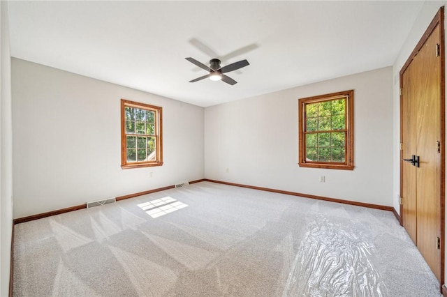 unfurnished bedroom featuring multiple windows, light colored carpet, and baseboards