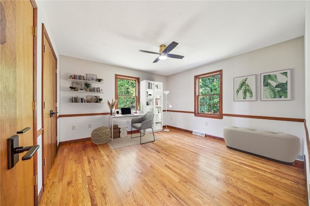 home office featuring light wood finished floors, a ceiling fan, and baseboards