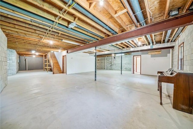 unfinished basement with stairway and concrete block wall
