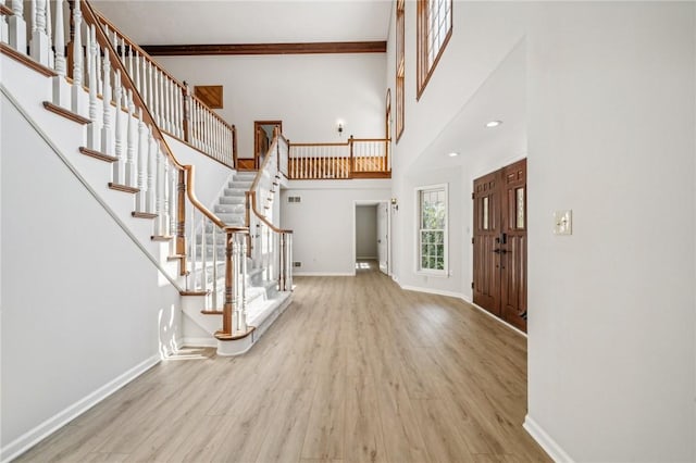 entrance foyer with wood finished floors, stairway, baseboards, and a towering ceiling