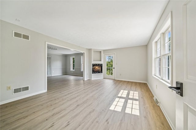 unfurnished living room with wood finished floors, plenty of natural light, and baseboards