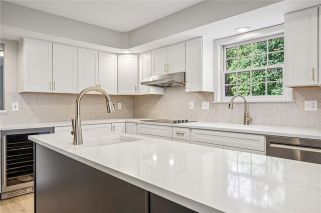 kitchen with beverage cooler, a sink, under cabinet range hood, stainless steel dishwasher, and light stone counters