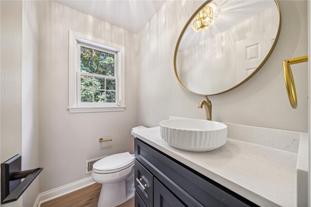 bathroom with vanity, toilet, baseboards, and wood finished floors