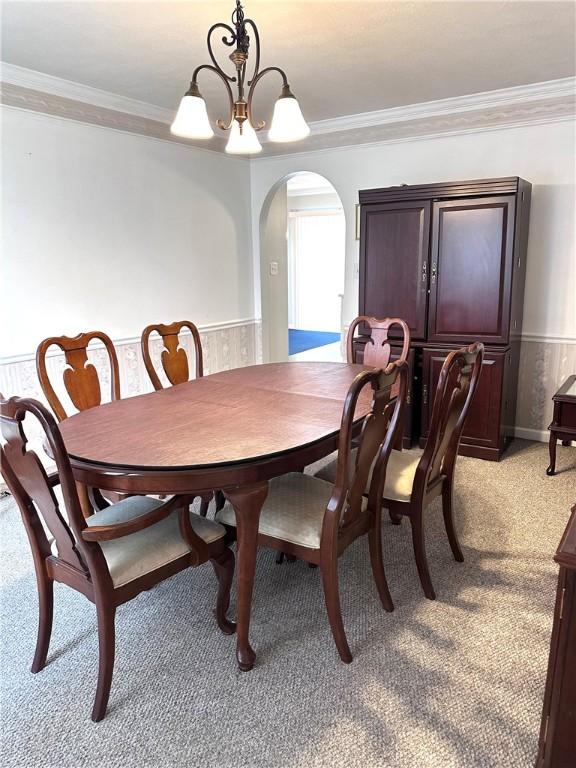 491 Peregrine Dr, North Huntingdon, PA 15642 - dining area with light colored carpet, arched walkways, crown molding, a wainscoted wall, and a chandelier