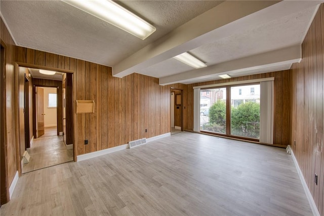710 4th Ave, Ford City Boro, PA 16226 - spare room featuring wooden walls, light wood-style flooring, a textured ceiling, beamed ceiling, and healthy amount of natural light