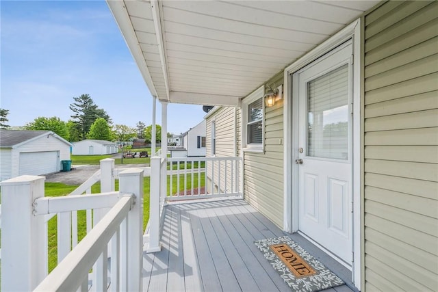 wooden deck featuring a porch, a detached garage, and a lawn