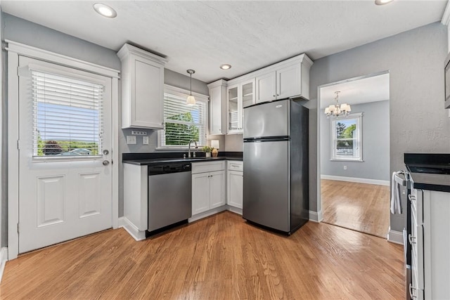 kitchen with appliances with stainless steel finishes, dark countertops, white cabinets, healthy amount of natural light, and recessed lighting