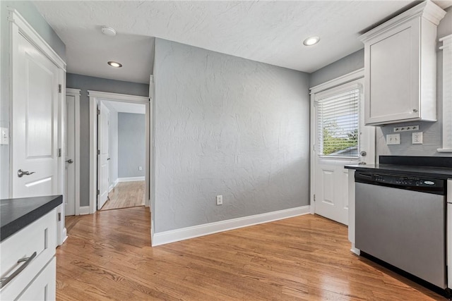 kitchen featuring dishwasher, dark countertops, light wood-type flooring, white cabinets, and baseboards