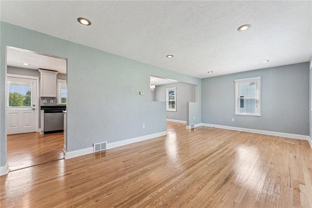 unfurnished living room with light wood finished floors, baseboards, and recessed lighting