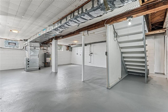 basement with water heater, heating unit, concrete block wall, and healthy amount of natural light