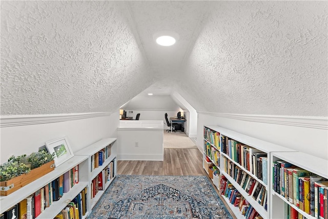 sitting room featuring a textured ceiling, vaulted ceiling, and wood finished floors