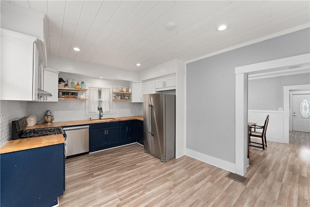 kitchen featuring appliances with stainless steel finishes, wooden counters, open shelves, blue cabinets, and a sink