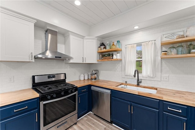 kitchen featuring appliances with stainless steel finishes, wall chimney exhaust hood, butcher block counters, a sink, and open shelves