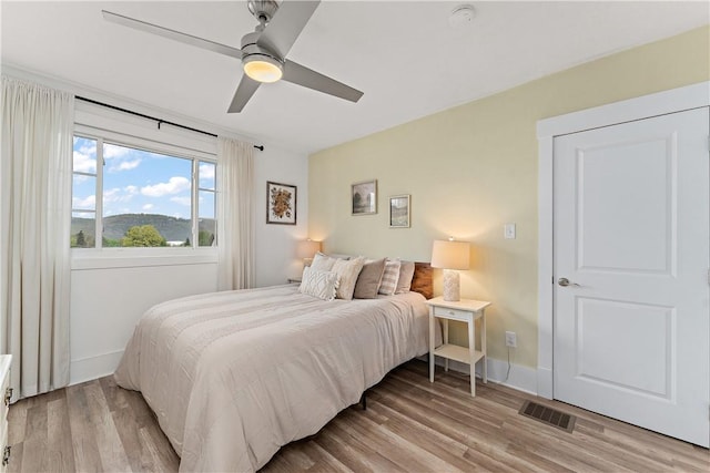 bedroom with light wood finished floors, baseboards, and ceiling fan