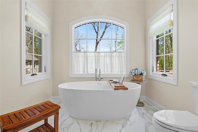 149 Walnut Ridge Dr, Chippewa Twp, PA 15010 - bathroom featuring marble look tiles, a freestanding bath, baseboards, and toilet