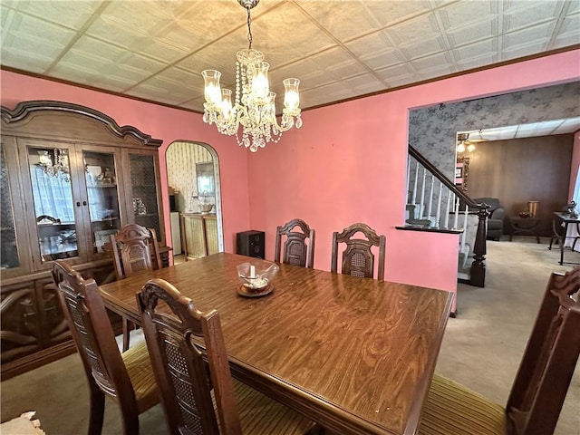 dining room featuring carpet flooring, a chandelier, arched walkways, an ornate ceiling, and stairway