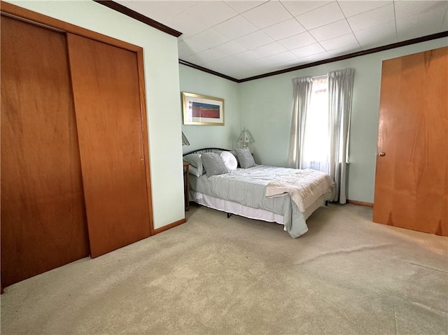 carpeted bedroom with crown molding, a closet, and baseboards