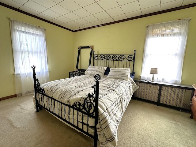 carpeted bedroom with ornamental molding and baseboards