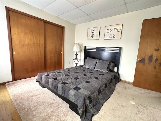 bedroom with a paneled ceiling, a closet, and baseboards