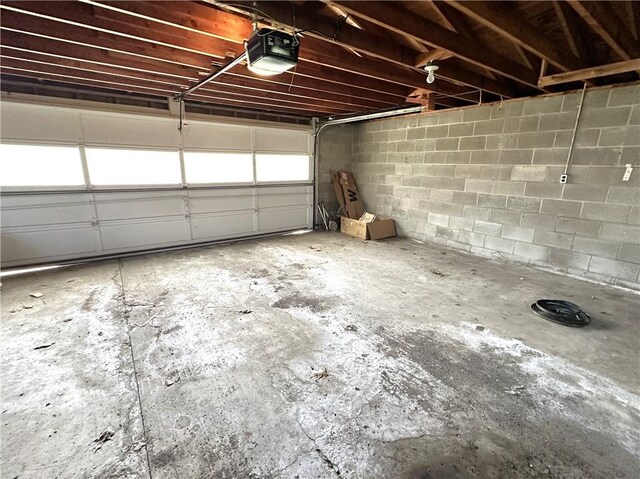 garage with a garage door opener and concrete block wall