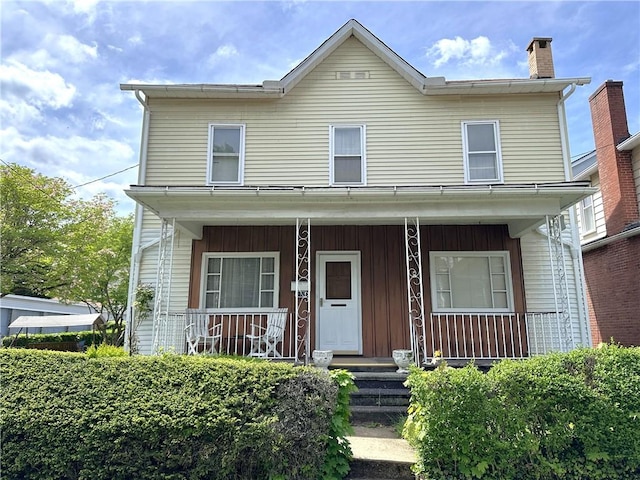 view of front facade featuring a chimney, a porch, and board and batten siding