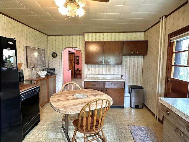 kitchen with black appliances, light countertops, arched walkways, crown molding, and light flooring