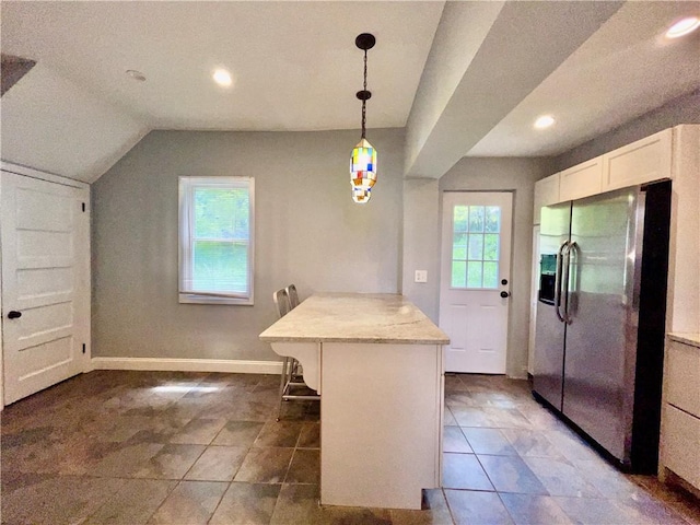 kitchen with stainless steel fridge, a breakfast bar, a peninsula, recessed lighting, and pendant lighting