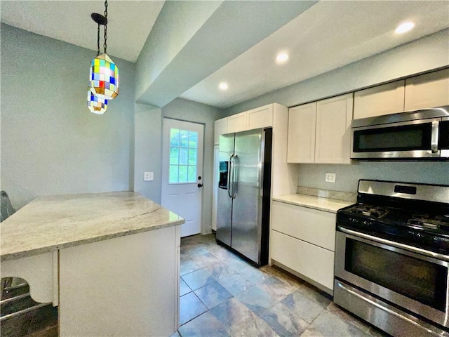 kitchen with appliances with stainless steel finishes, a peninsula, white cabinets, hanging light fixtures, and recessed lighting