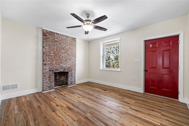 unfurnished living room with ceiling fan, baseboards, wood finished floors, and a brick fireplace