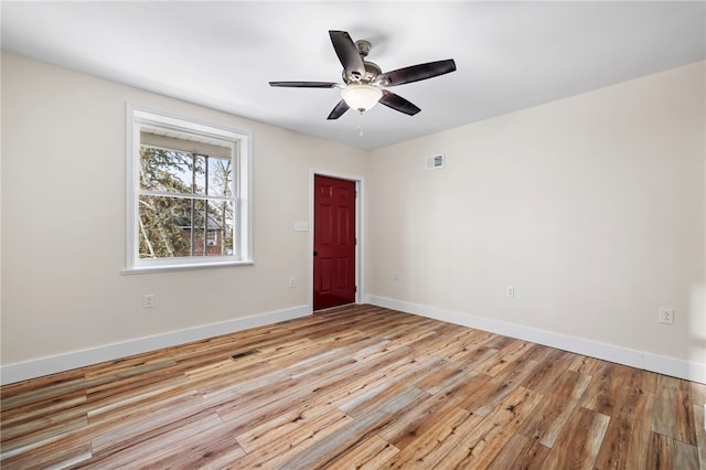 empty room with light wood finished floors, baseboards, and a ceiling fan