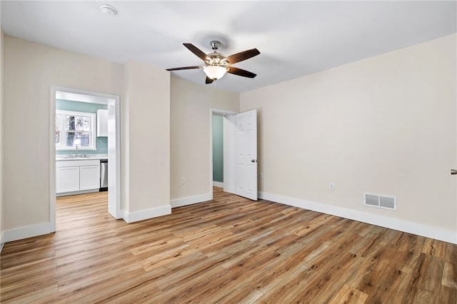 unfurnished room with light wood-style flooring, a ceiling fan, and baseboards