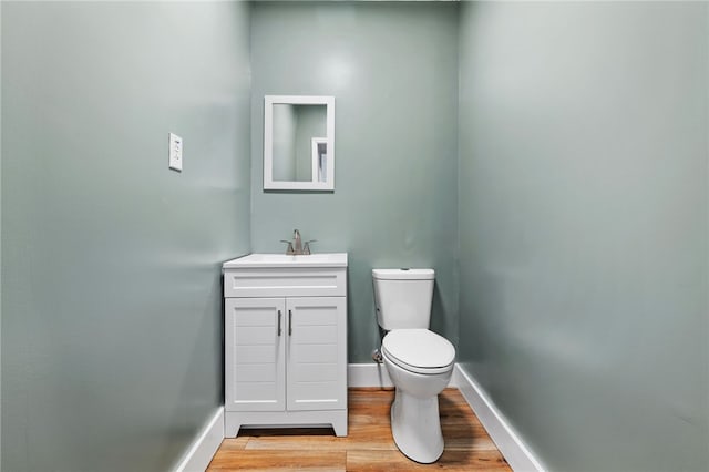 bathroom featuring toilet, wood finished floors, vanity, and baseboards