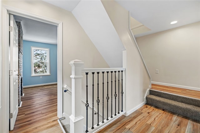 stairway with wood finished floors, baseboards, and recessed lighting