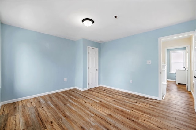 unfurnished bedroom featuring baseboards, light wood-style flooring, and a closet
