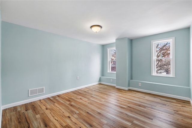 spare room with healthy amount of natural light, wood finished floors, and baseboards