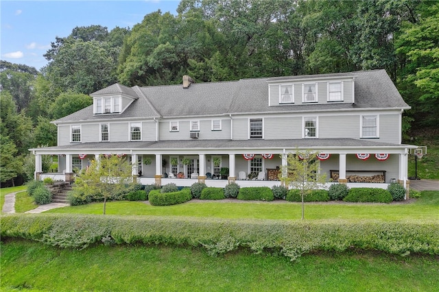 view of front of house with covered porch, a front lawn, and roof with shingles