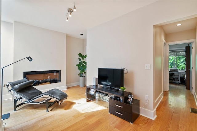 living area featuring light wood-type flooring, baseboards, and recessed lighting