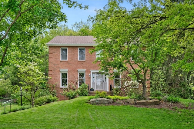 colonial-style house featuring brick siding and a front lawn