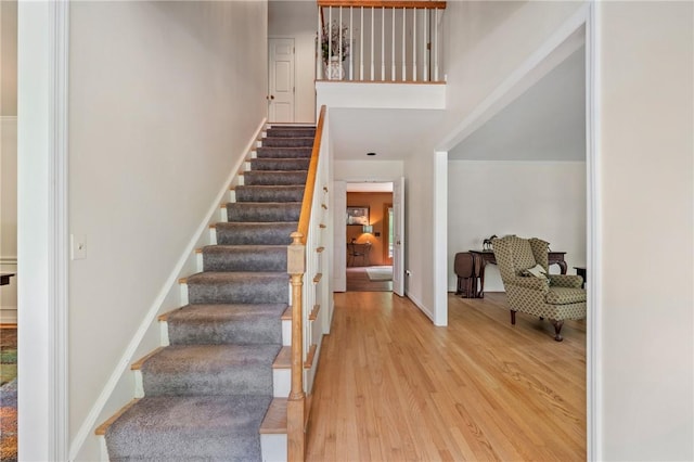 entrance foyer with light wood finished floors, stairs, baseboards, and a high ceiling