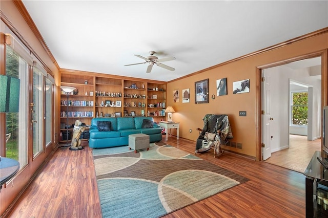living room featuring ornamental molding, a ceiling fan, wood finished floors, and baseboards