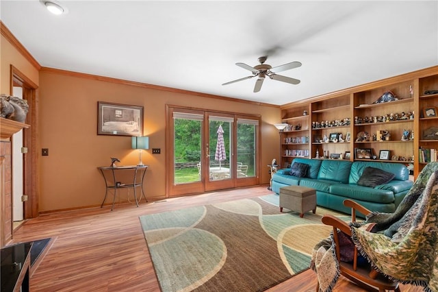 living room with a ceiling fan, light wood-type flooring, crown molding, and baseboards
