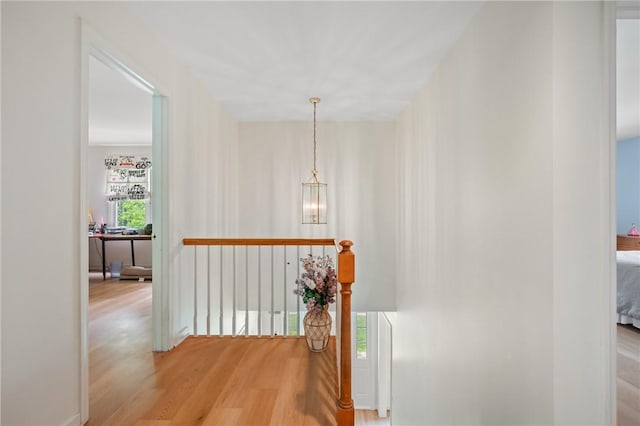 hall with an upstairs landing, light wood-style flooring, and a chandelier